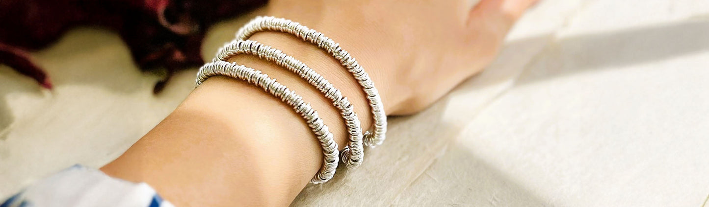 Image of a hand with three chunky silver ring bracelets