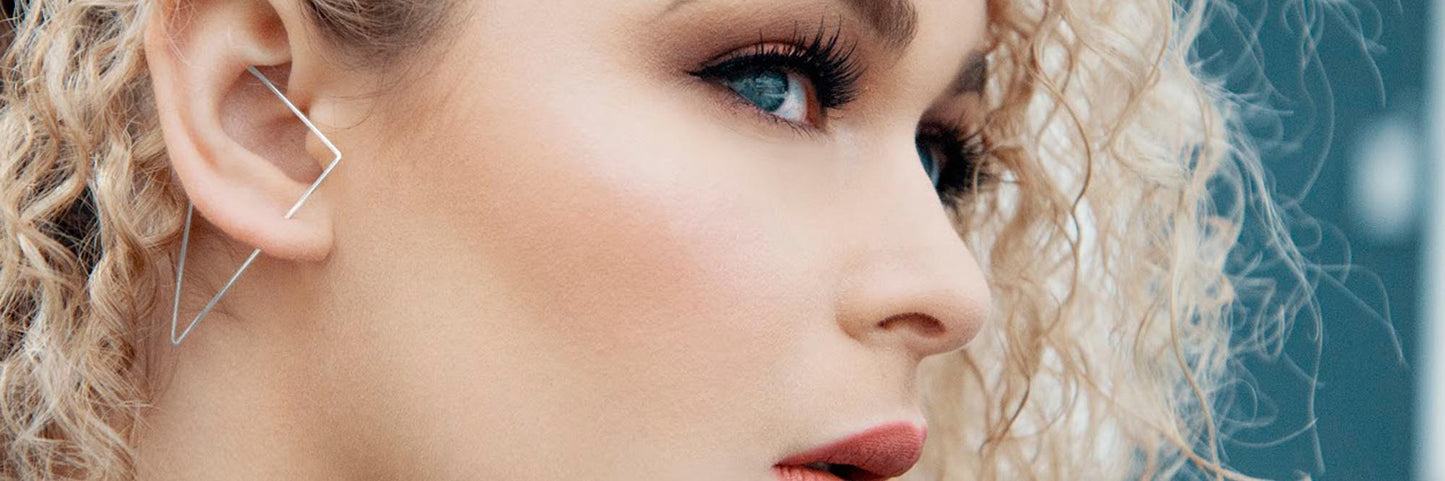Close up image of a blond model with a silver triangle ear cuff in place