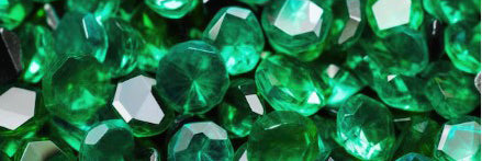 Close-up of faceted emerald gemstones showcasing rich green colour and reflective cuts. May birthstone detail