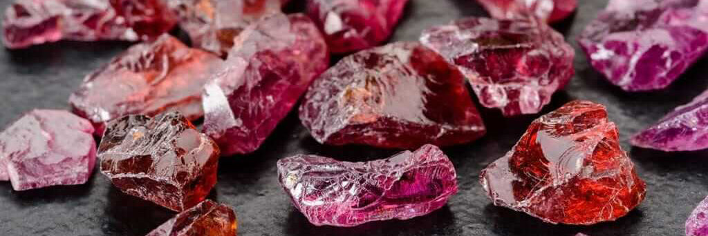 Close-up of raw garnet gemstones showcasing rich red colours and reflective cuts. January birthstone detail