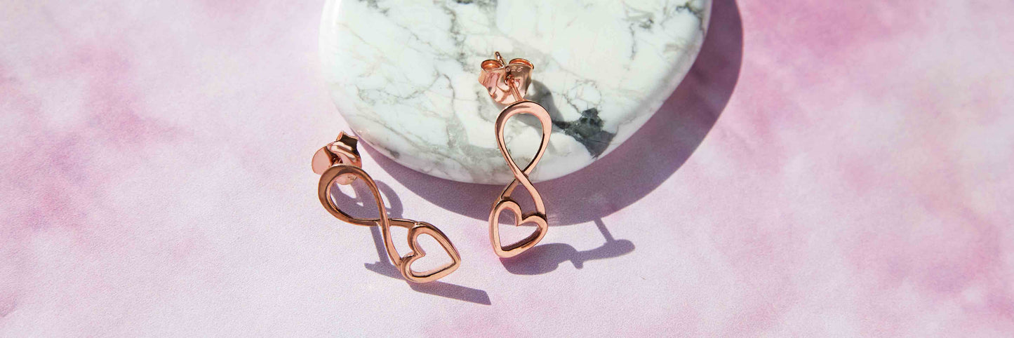 Image of Rose Gold Infininity Heart drop Earrings on a marble stone background