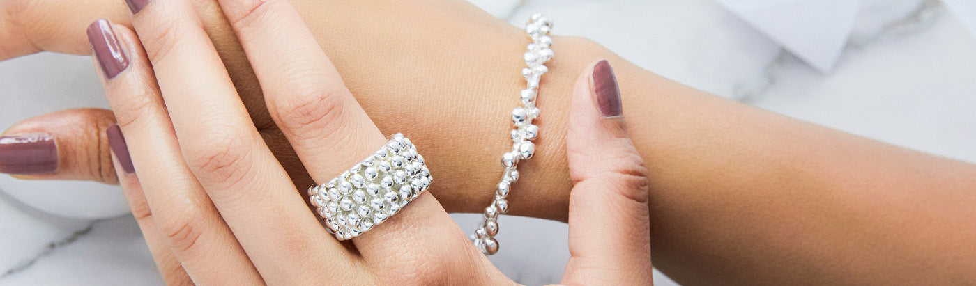 A textured statement ring with bobble like detail being worn on a womans hand