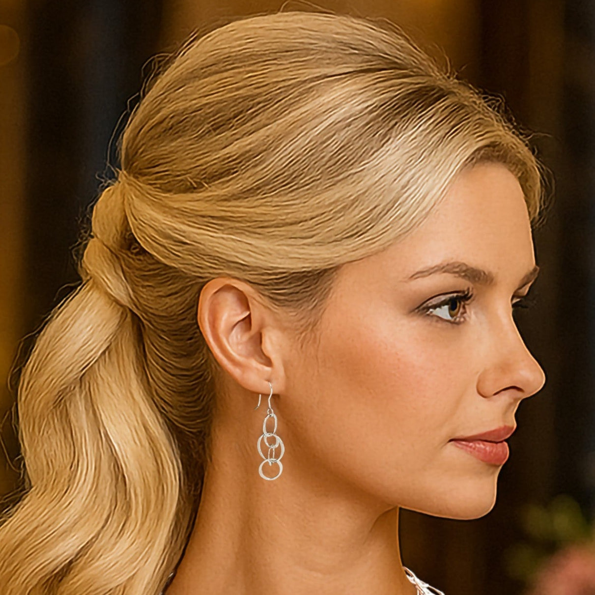 Woman in a pink dress with a floral background and matching long chain earrings and necklace